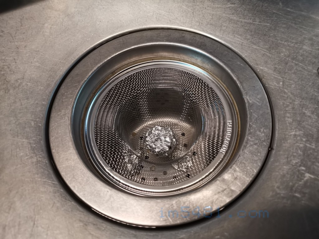 廚房水槽排水濾網上方放一個不鏽鋼濾網，並且在濾網上放上一顆圓形鋁箔球