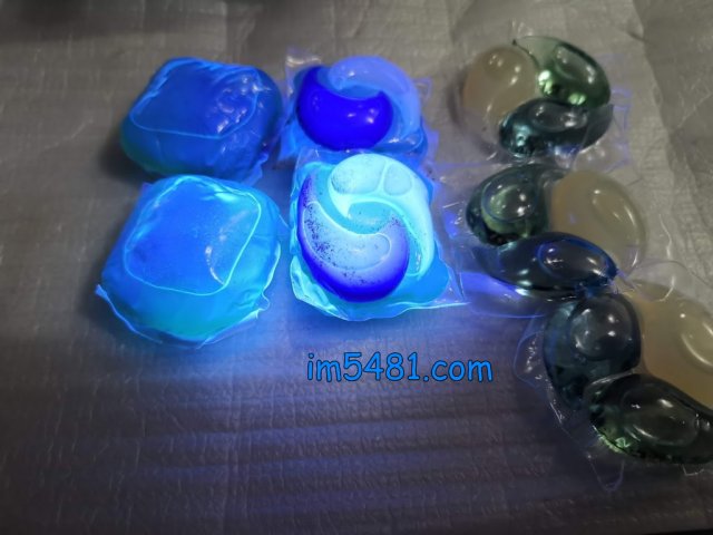 紫外線燈照射左邊跟中間的洗衣膠囊。（兩者都有螢光增白劑）